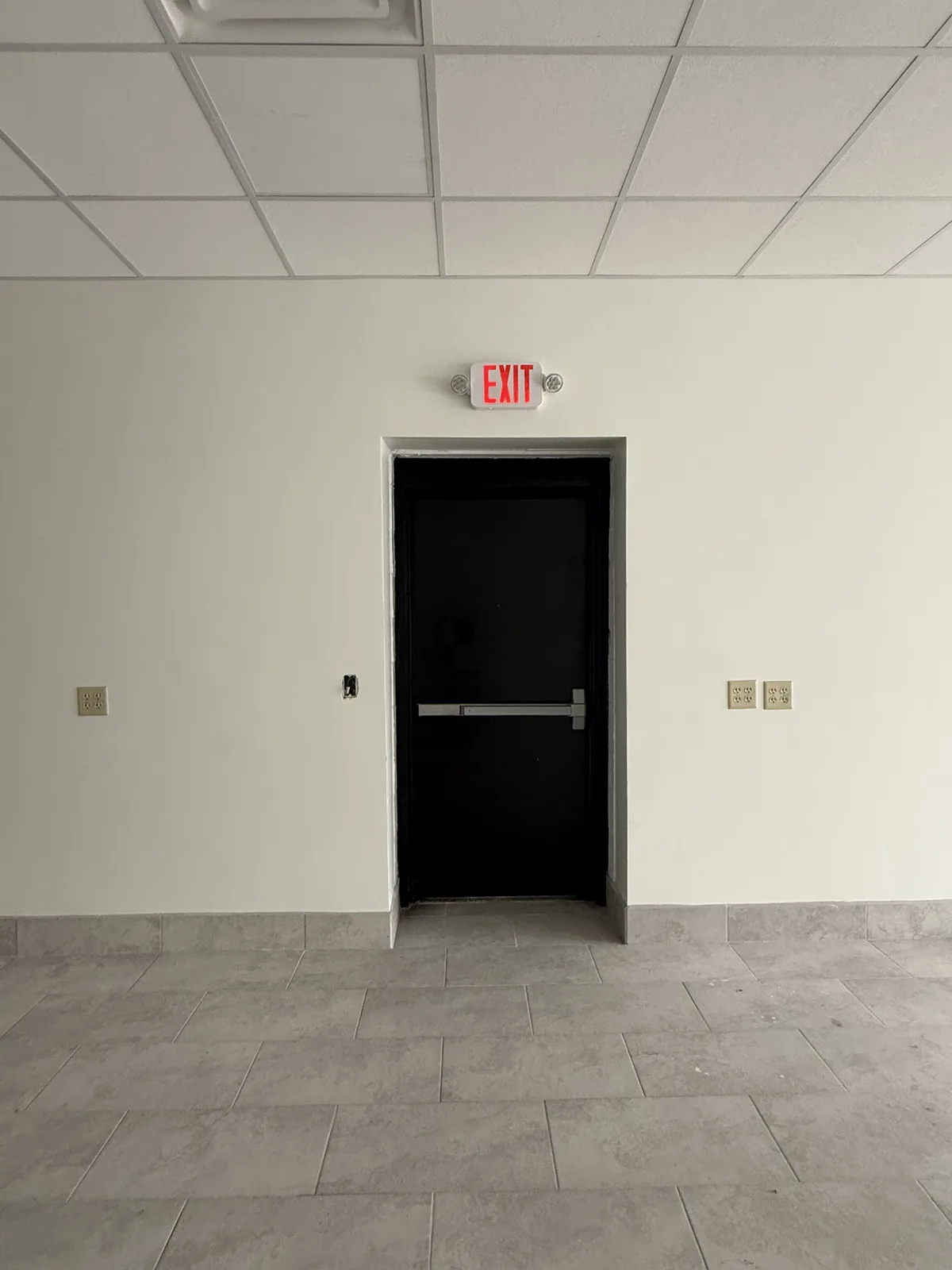 Unit 4’s steel exit door, with a push bar and a lit exit sign